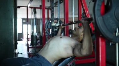 Büyük kaslı Asyalı adam spor salonunda ağırlık çalışması yapıyor.