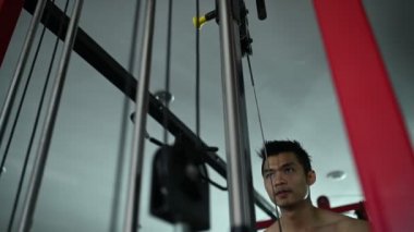 Büyük kaslı Asyalı adam spor salonunda ağırlık çalışması yapıyor.