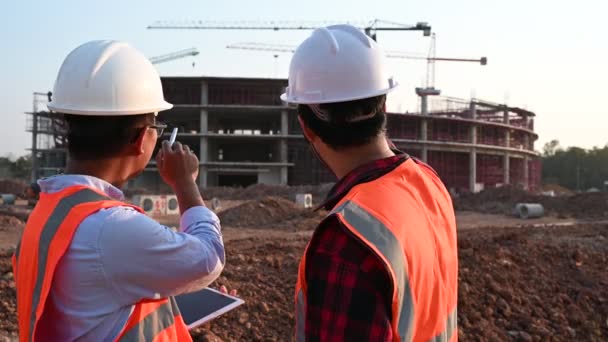 建設現場で働く2人のエンジニアが助け合いながら問題を分析する — ストック動画