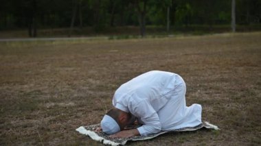 Asyalı genç Müslüman adam dışarıda dua ediyor, Ramazan festivali konsepti.