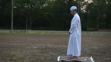 Asyalı genç Müslüman adam dışarıda dua ediyor, Ramazan festivali konsepti.