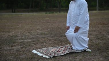 Asyalı genç Müslüman adam dışarıda dua ediyor, Ramazan festivali konsepti.