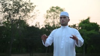Asyalı genç Müslüman adam dışarıda dua ediyor, Ramazan festivali konsepti.