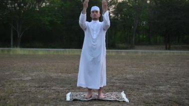 Asyalı genç Müslüman adam dışarıda dua ediyor, Ramazan festivali konsepti.