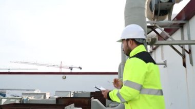 Klima teknisyeni binanın dışındaki birimleri tamir ediyor ve muhafaza ediyor.