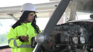 Kadın teknisyen uçağın motorunu tamir ediyor.