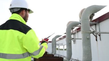 Klima teknisyeni binanın dışındaki birimleri tamir ediyor ve muhafaza ediyor.