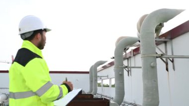 Büyük bir fabrikanın atık su yönetim sisteminde Asyalı bakım mühendisi, ısıtma sistemi ekipmanlarının teknik verilerini kontrol ediyor.