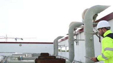 Büyük bir fabrikanın atık su yönetim sisteminde Asyalı bakım mühendisi, ısıtma sistemi ekipmanlarının teknik verilerini kontrol ediyor.