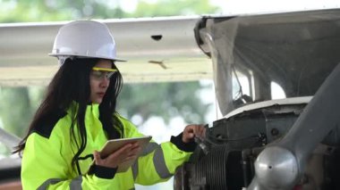 Kadın teknisyen uçağın motorunu tamir ediyor.