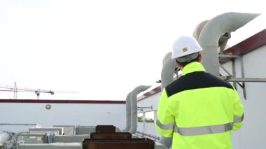 Klima teknisyeni binanın dışındaki birimleri tamir ediyor ve muhafaza ediyor.