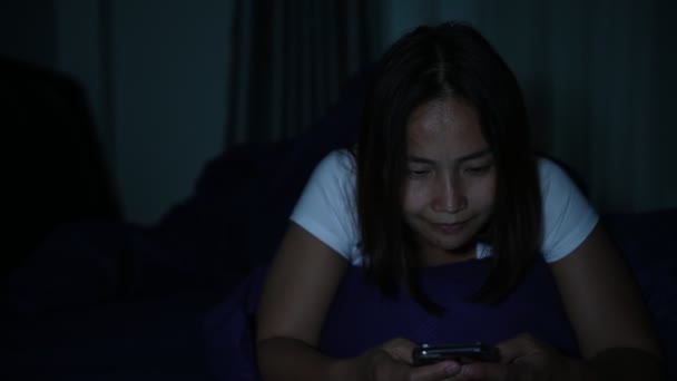 アジアの女性は夜にベッドでスマートフォンを — ストック動画