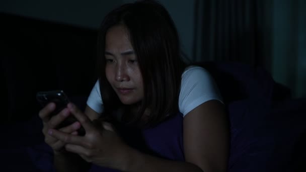 アジアの女性は夜にベッドでスマートフォンを — ストック動画