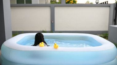 Evdeki havuzda yüzen küçük kız.