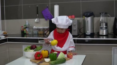 Mutfak odasındaki masada bir sürü sebze bulunan şef üniforması giyen tatlı Asyalı kız.