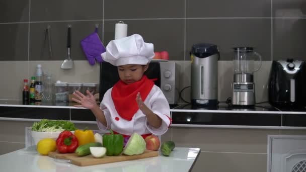 可爱的亚洲女孩穿着厨师制服 桌上放着很多蔬菜 — 图库视频影像