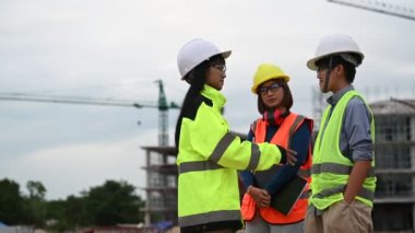 Genç ve kıdemli mühendisler inşaat halindeki büyük bina çalışmalarını tartışıyorlar.