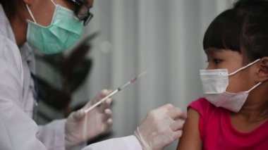 Virüsü koruyan Asyalı doktor enjeksiyon aşısı covid-19 tıbbi maske takıyor
