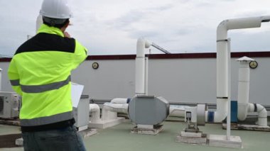 Klima teknisyeni binanın dışındaki birimleri tamir ediyor ve muhafaza ediyor.