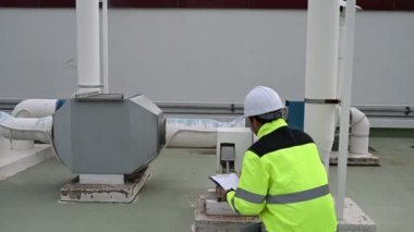 Klima teknisyeni binanın dışındaki birimleri tamir ediyor ve muhafaza ediyor.