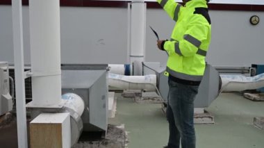 Klima teknisyeni binanın dışındaki birimleri tamir ediyor ve muhafaza ediyor.