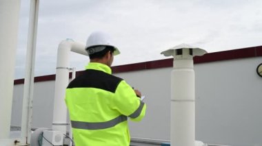 Klima teknisyeni binanın dışındaki birimleri tamir ediyor ve muhafaza ediyor.