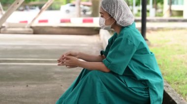 Depresyonda olan Asyalı hemşire kadın yüz maskesi takıyor ve mavi üniforma giyiyor.