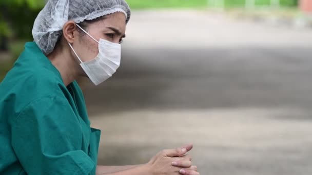 顔のマスクとハードワークからの青い均一なストレスを身に着けている疲れ落ち込んで女性アジアのスクラブ看護師 — ストック動画