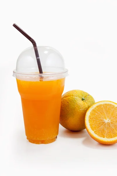 Jus d'orange in plastic duidelijk beker en oranje vruchten — Stockfoto