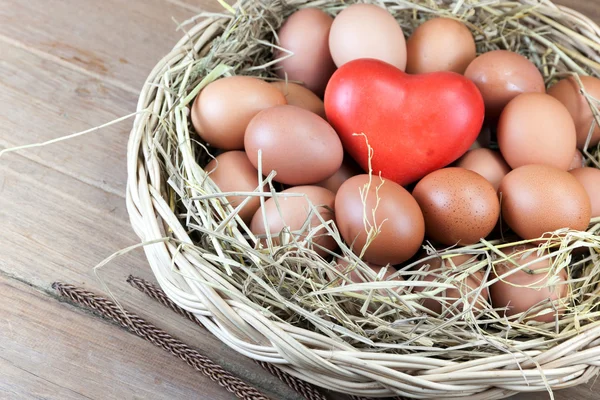 Яйца и красное сердце в корзине — стоковое фото