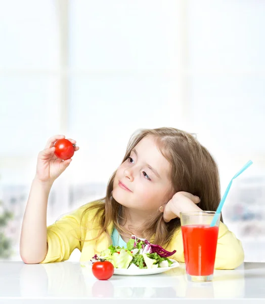 Kind meisje eten tomaten frisse salade lege ruimte achtergrond. — Stockfoto