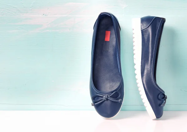 Ολίσθησης στην θηλυκά μπλε επίπεδη παπούτσια σε φόντο ξύλινη. — Φωτογραφία Αρχείου
