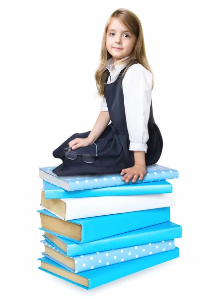 Niña de la escuela infantil sentada en pila pila de libros aislados . — Foto de Stock