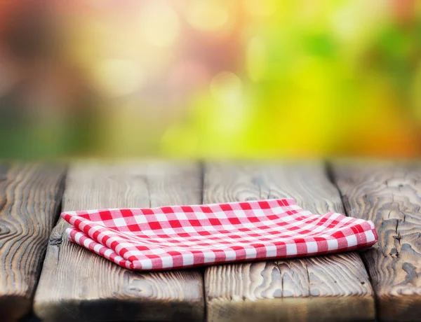 Red picnic cloth on wooden table mature bokeh background. — Stock Photo, Image