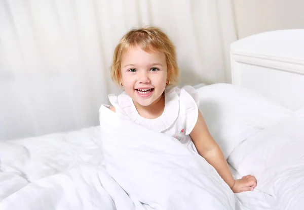 ベッドの笑顔の顔の子供の女の子 幸せな子供の良い朝のコンセプト — ストック写真