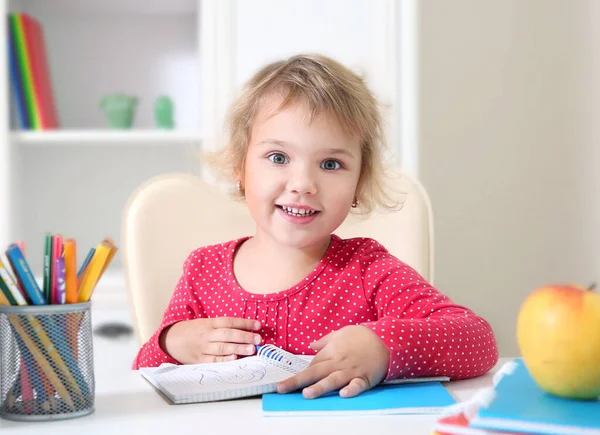 Μικρό Χαμογελαστό Κορίτσι Που Κάθεται Στο Τραπέζι Και Ζωγραφίζει Σημειωματάριο — Φωτογραφία Αρχείου