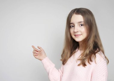 Güzel insan reklam tasarımı boş. Parmak arası boş bir yer gösteren genç bir kız. Kafkasyalı genç nokta gri arkaplan..