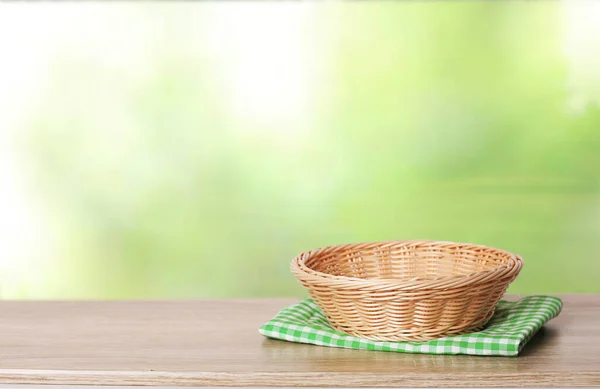 Straw empty basket on wooden table with  copy space.Green natural product display.Food advertisement design.