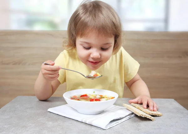Child eating soup.Caucasian little girl sitting at table and have a meal. Healthy nutrition. Home made dinner.