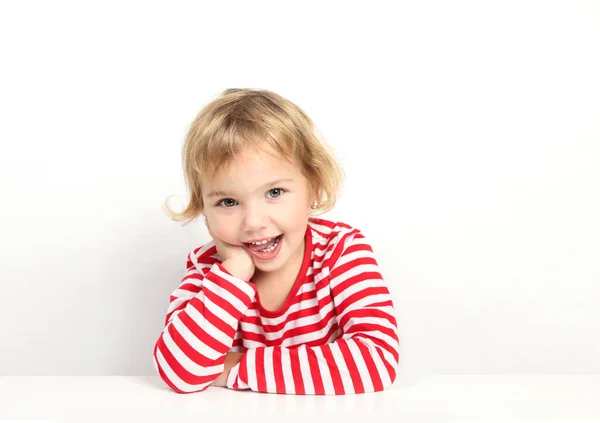 空の白いテーブルに座っている子供の女の子 昇進するためにかわいい顔の空のスペース笑顔の女の子 子供の肖像広告デザイン 白人の幼児 — ストック写真