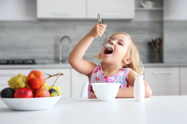 テーブル席に座って食事を楽しんでいる小さな白人の女の子 子供は食事をする 有機朝食 健康的な栄養の概念 子供は朝ご飯を食べる — ストック写真