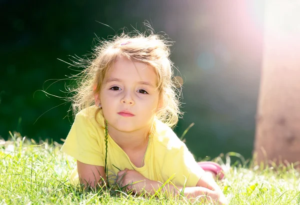 緑 grass.child 屋外クローズ アップ顔の上に横たわる少女. — ストック写真