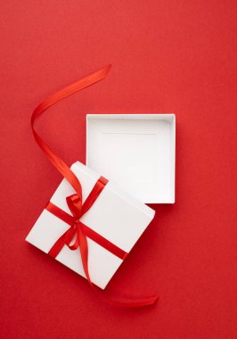 Kırmızı kurdeleyle süslenmiş tek bir beyaz kare hediye kutusu. Boş reklam alanı. Mevcut kutulanmamış ürün tanıtım şablonu, ekran. Konteynır dikey arkaplan.