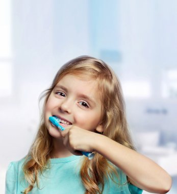 Child girl toddler cleaning teeth in bathroom background. clipart