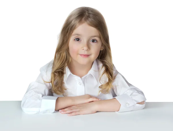 Девочка из детской школы, сидящая на белом столе . — стоковое фото