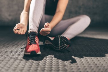 Ayakkabı bağcıklarını bağlayan koşucu kadının yakın çekimi..
