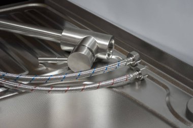 Mutfak musluğunun lavaboya kurulumu. Bir mutfak musluğu kurulum için hortumlarla donatılmıştır.