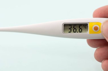 Fotoğraf, insan eliyle 36.6 derece sıcaklıkta bir termometre gösteriyor.