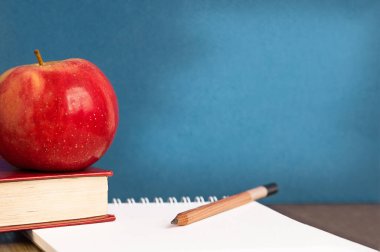 Okula dönelim. Fotoğrafta bir elma, bir kitap, fotokopi alanı olan bir kalem var.