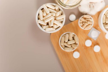 Kahverengi arka planda insan sağlığı ve bağışıklık sistemini destekleyen besin takviyeleri ve vitaminler. Omega 3, chelated magnezyum, çinko, C vitamini, multivitamin kompleksi gibi organik vitaminler var. Vitaminler ve besin takviyeleri ahşap masada.